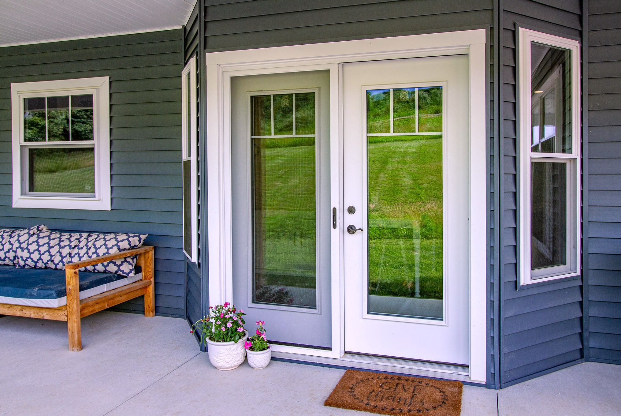 White hinged patio doors on blue-gray sided porch with bench