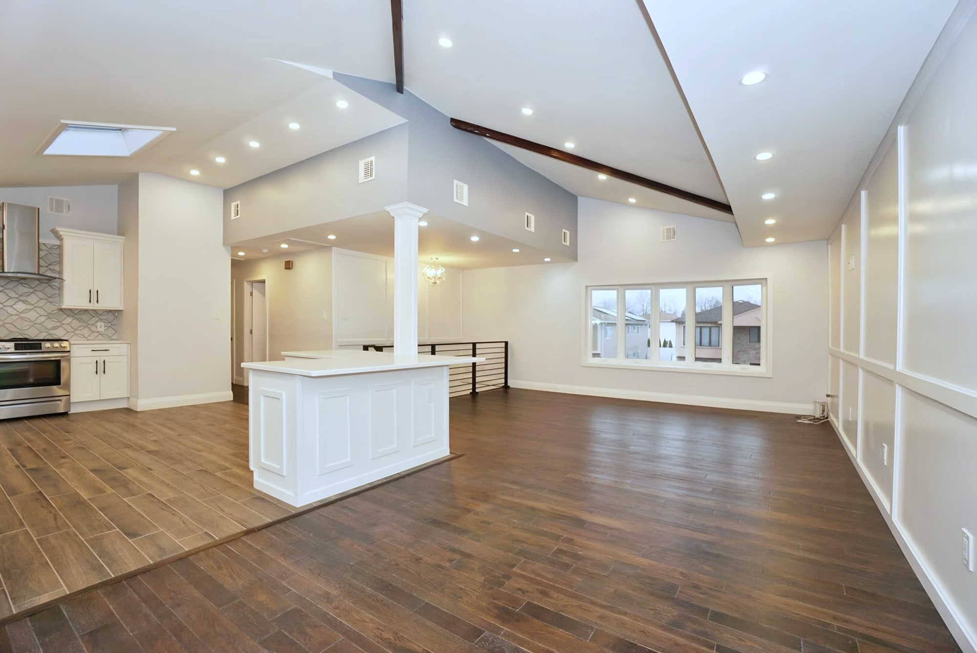 Open-plan renovated interior with kitchen, island, wood-look floor, vaulted ceiling